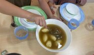 Kinder bedienen sich mit Suppe am eingedeckten Tisch 