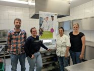 Vier Personen stehen in einer Küche.