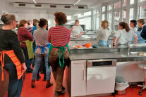 Personen stehen in einer Großküche
