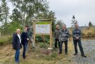 Ehrengäste stehen an einer Tafel des Waldumbauparcours