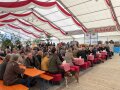 Besucher der Eröffnungsveranstaltung sitzen im Festzelt