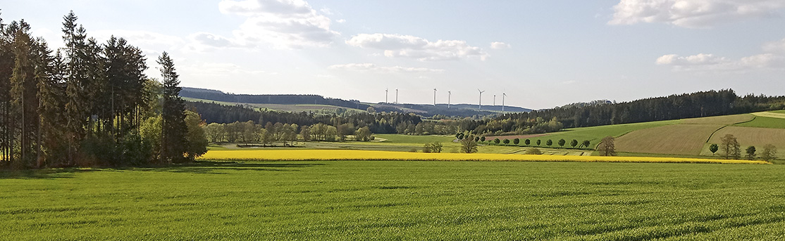 Sommerliche Landschaft mit Feldern, Wäldern und Windrädern