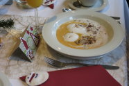 Teller mit Suppe auf weihnachtlich dekoriertem Tisch