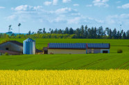 Hof mit Solaranlagen und Windrad im Hintergrund 