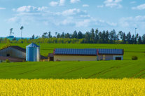 Hof mit Solaranlagen und Windrad im Hintergrund